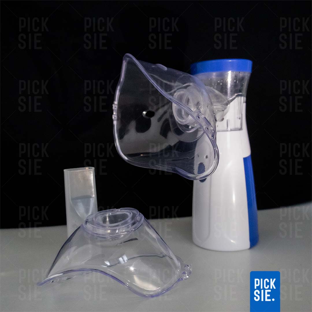 Two clear inhaler masks and a white and blue canister on a gray surface with 'PICK SIE.' branding.